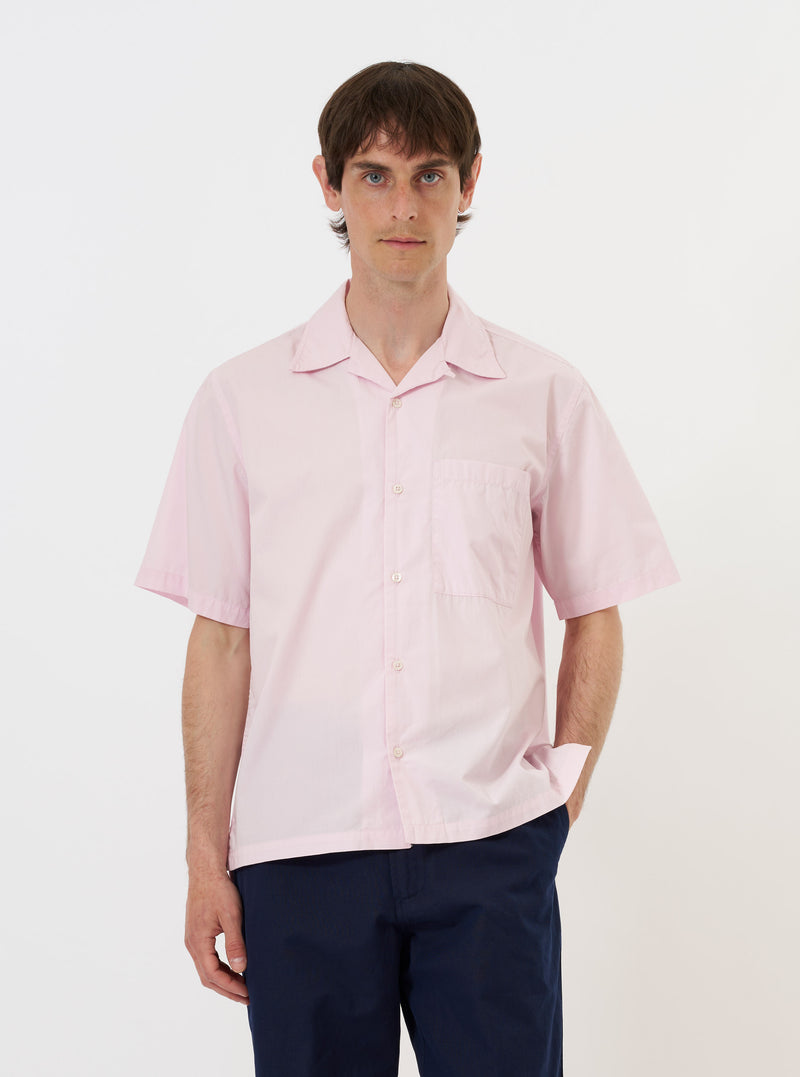 A Pale Pink Broadcloth Camp Shirt is shown laid flat against a solid white background. The garment features a relaxed camp collar, a full button-down front with tonal buttons, short sleeves, and a straight hem. The light pink cotton fabric has a smooth, matte finish.