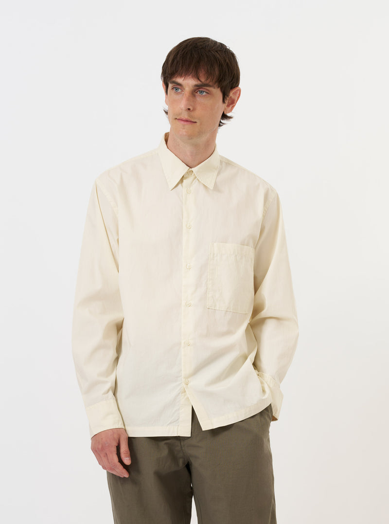 The Ecru Broadcloth Lucky Shirt is displayed flat against a plain white background. The garment is a short-sleeved button-down shirt featuring a relaxed fit, a classic pointed collar, and a straight hem. The fabric is a solid ecru or off-white color with a smooth broadcloth texture.