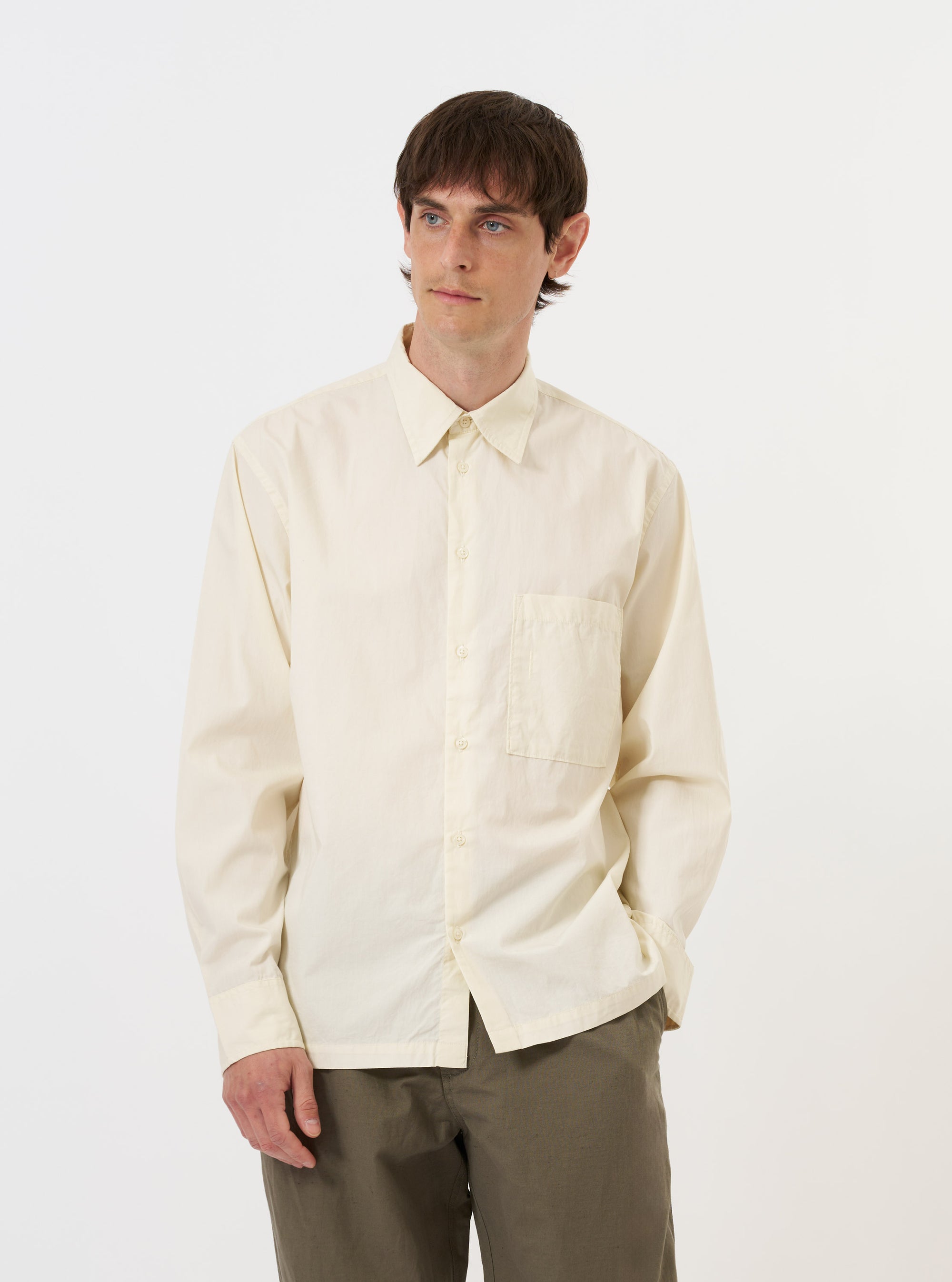 The Ecru Broadcloth Lucky Shirt is displayed flat against a plain white background. The garment is a short-sleeved button-down shirt featuring a relaxed fit, a classic pointed collar, and a straight hem. The fabric is a solid ecru or off-white color with a smooth broadcloth texture.