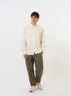 The Ecru Broadcloth Lucky Shirt is shown laid flat against a solid white background. The garment features a cream-colored cotton broadcloth fabric, a classic pointed collar, a full button-down front, and short sleeves. A single patch pocket is visible on the left chest.