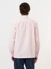 A model is wearing the Pale Pink Broadcloth Lucky Shirt against a plain white background. The shirt is shown from the back, highlighting the yoke, the hang loop, and the relaxed fit of the pale pink broadcloth fabric. The model is also wearing dark trousers.