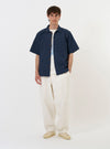 The Navy Chester Stripe S/S Fatigue Shirt is displayed flat against a plain white background. The short-sleeved overshirt features a navy and white vertical stripe pattern, a classic pointed collar, and a full button-down front. A prominent, slightly lowered patch pocket is visible on the left chest.