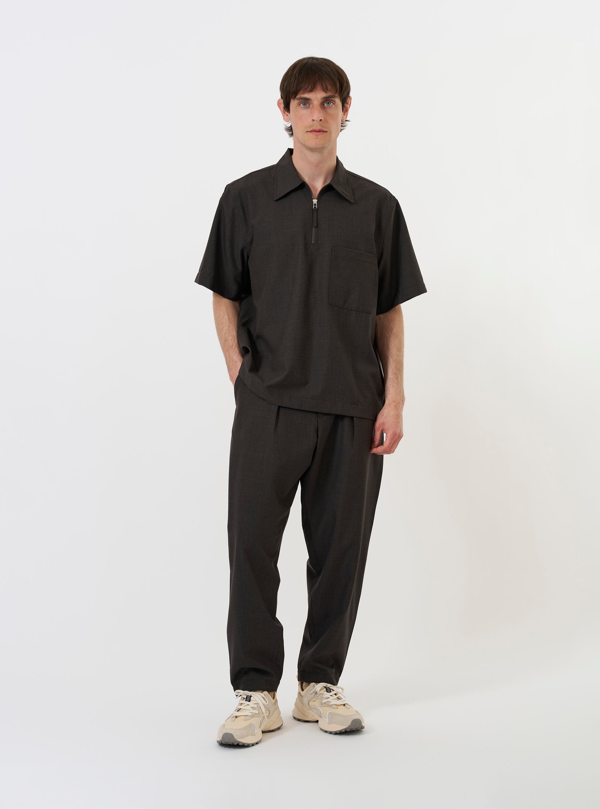 The Brown Marl Tropical Suiting Ewan Shirt is shown laid flat against a plain white background. The garment features a half-zip front, a classic pointed collar, a straight hem, and a single chest pocket on the left side. The fabric has a fine, textured brown marl finish.