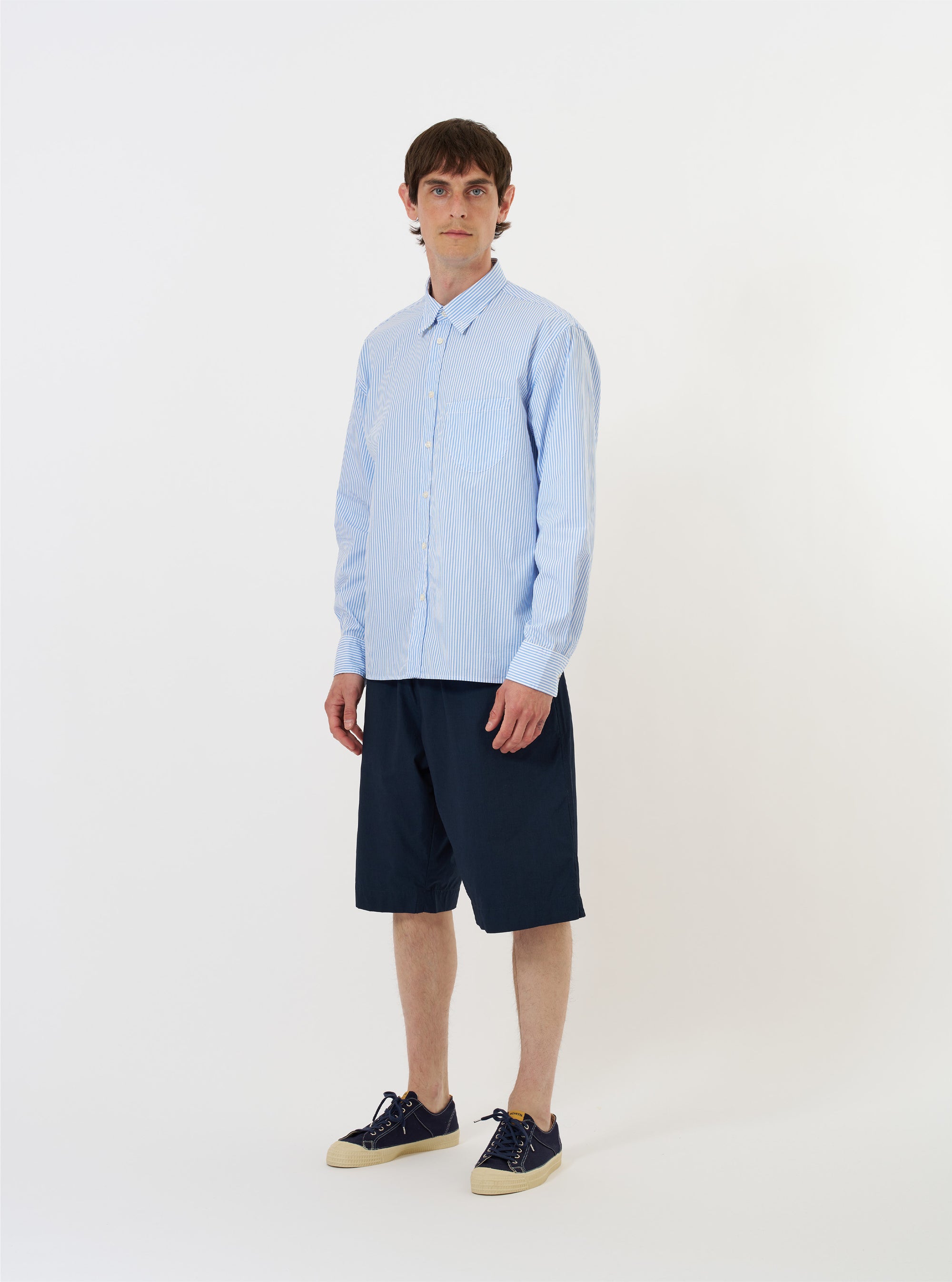 The Sky/White Classic Nipon Stripe Lazy Day Shirt is shown laid flat against a plain white background. The long-sleeve shirt features a vertical light blue and white stripe pattern, a classic pointed collar, and a full button-down front. A single asymmetric chest pocket is visible on the left side.