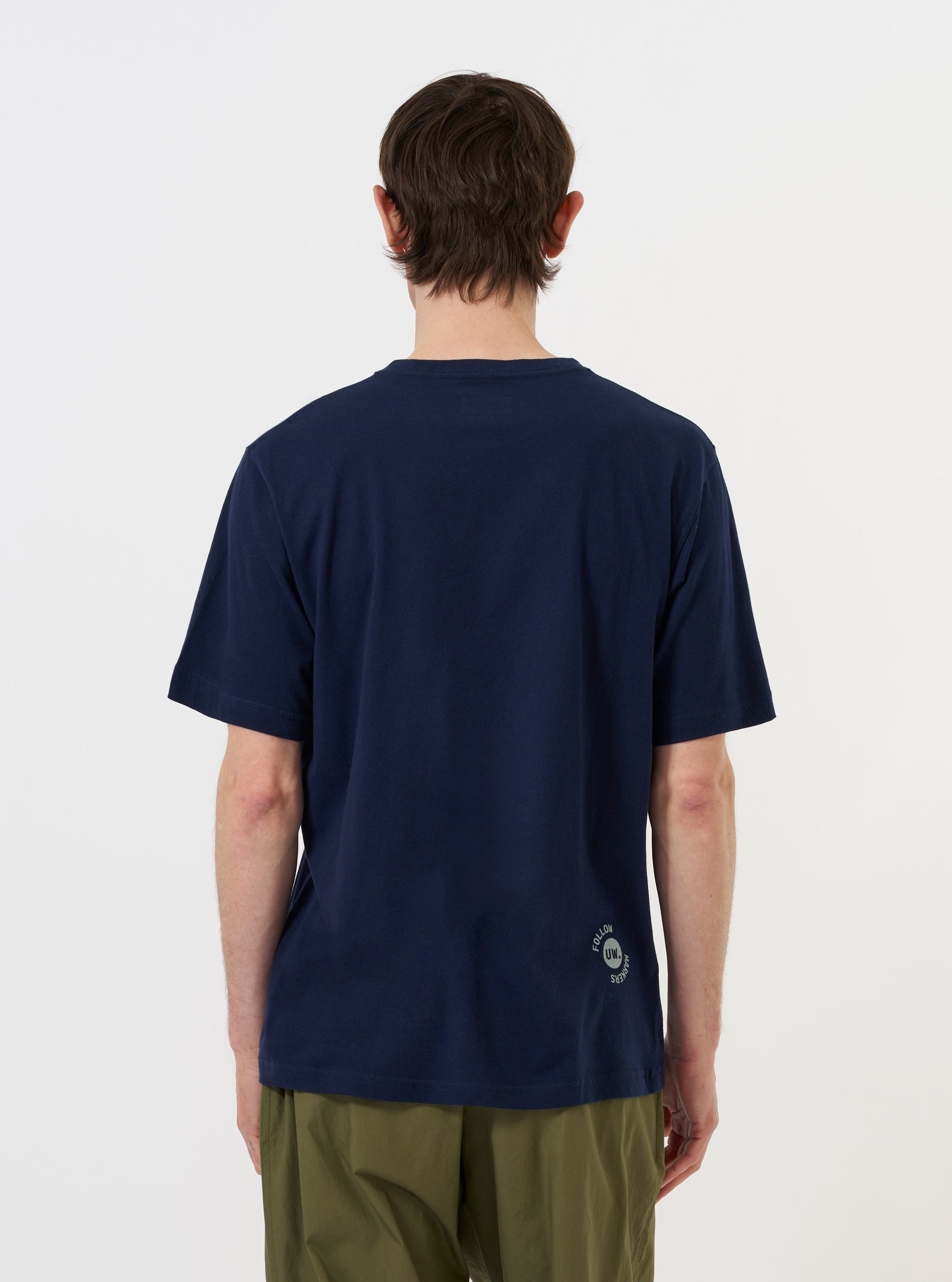 A model is shown from the back wearing the Navy Single Jersey Trail Trail To Hotel Delux Tee against a plain white background. The navy blue t-shirt features a relaxed fit, short sleeves, and a clean, straight hem. No other garments or accessories are visible.