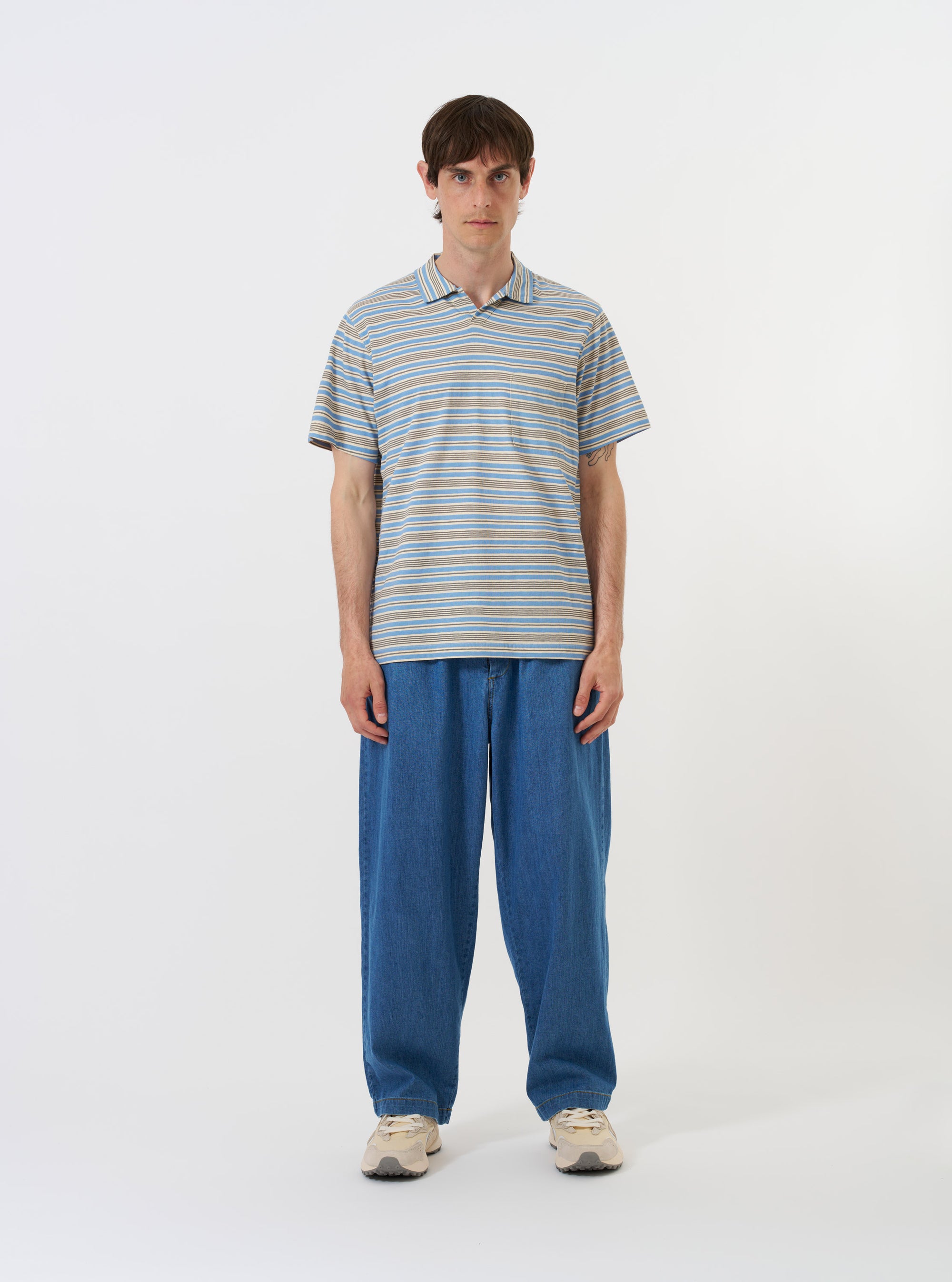The Pale Blue OS Stripe Jersey Vacation Polo is shown laid flat against a solid white background. The garment features horizontal light blue and white stripes, a relaxed open-neck collar with a short placket, short sleeves, and a single patch pocket on the left chest.