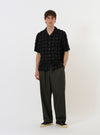 The Black 3D Check Road Shirt is shown laid flat against a solid white background. The short-sleeve shirt features a dark grey and black 3D-effect check pattern, a relaxed camp collar, a full button-down front, and a single patch pocket on the left chest. The hem is straight.