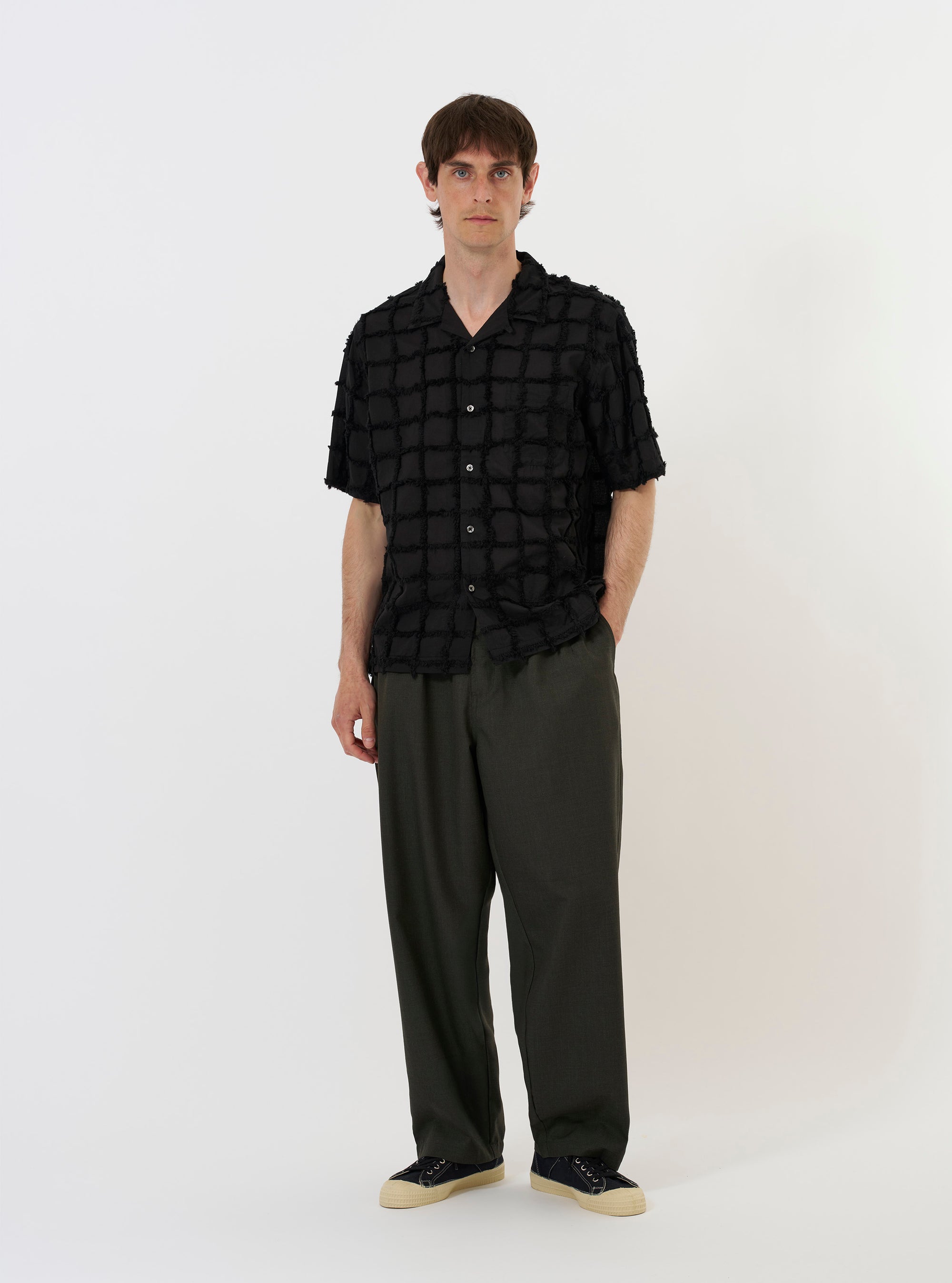 The Black 3D Check Road Shirt is shown laid flat against a solid white background. The short-sleeve shirt features a dark grey and black 3D-effect check pattern, a relaxed camp collar, a full button-down front, and a single patch pocket on the left chest. The hem is straight.