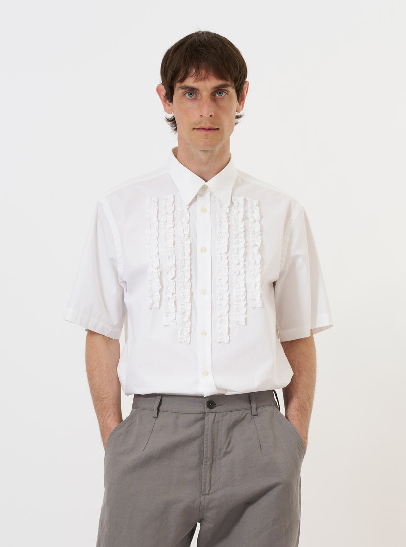 The White Poplin Frill Shirt is displayed flat against a solid white background. The shirt features a classic collar with prominent frill detailing along the edge, a full button-down front, and long sleeves with buttoned cuffs. The fabric is a crisp white cotton poplin.