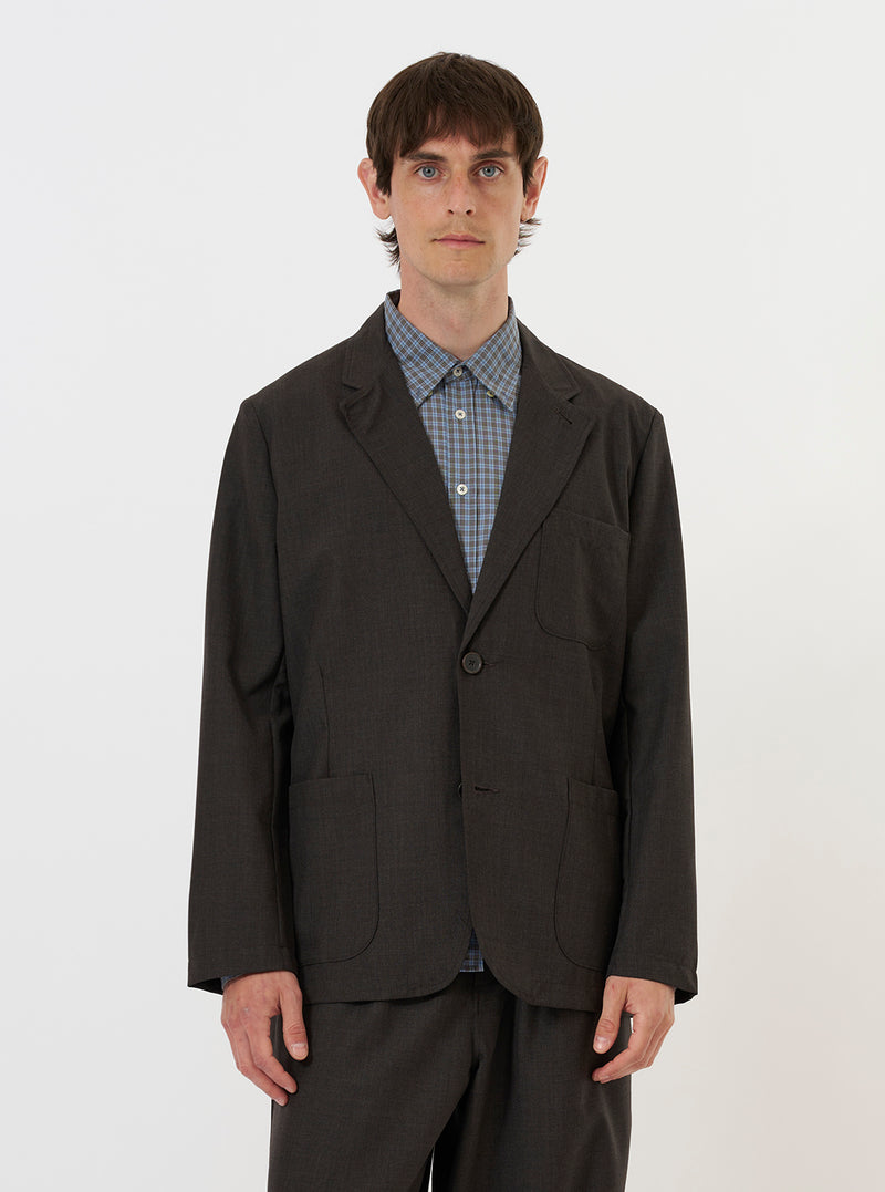 A model is wearing the Brown Marl Tropical Suiting Two Button Jacket against a plain white background. The image shows the model from the chest down, highlighting the jacket's relaxed fit, brown marl texture, two-button front fastening, and lower patch pockets.