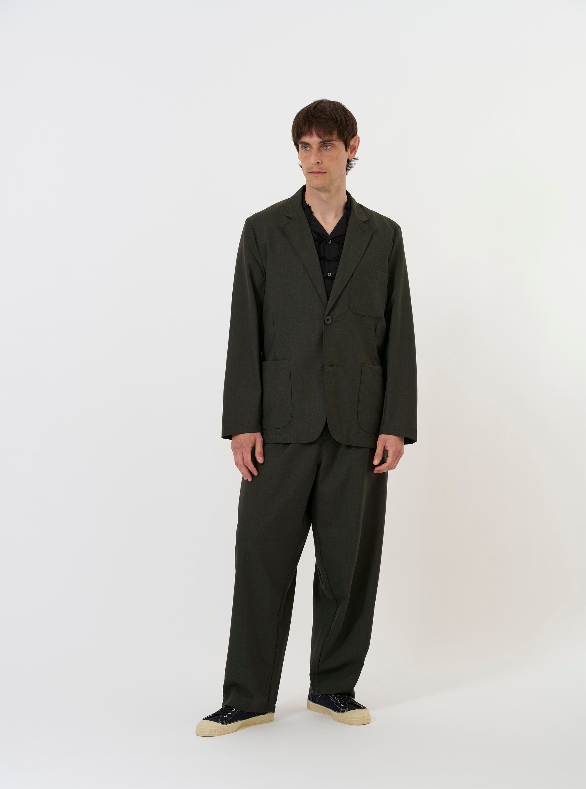 The Olive Marl Tropical Suiting Two Button Jacket is shown laid flat against a solid white background. The jacket features notch lapels, a two-button front closure, and two large patch pockets at the hips. The olive green marl fabric has a subtle textured appearance.