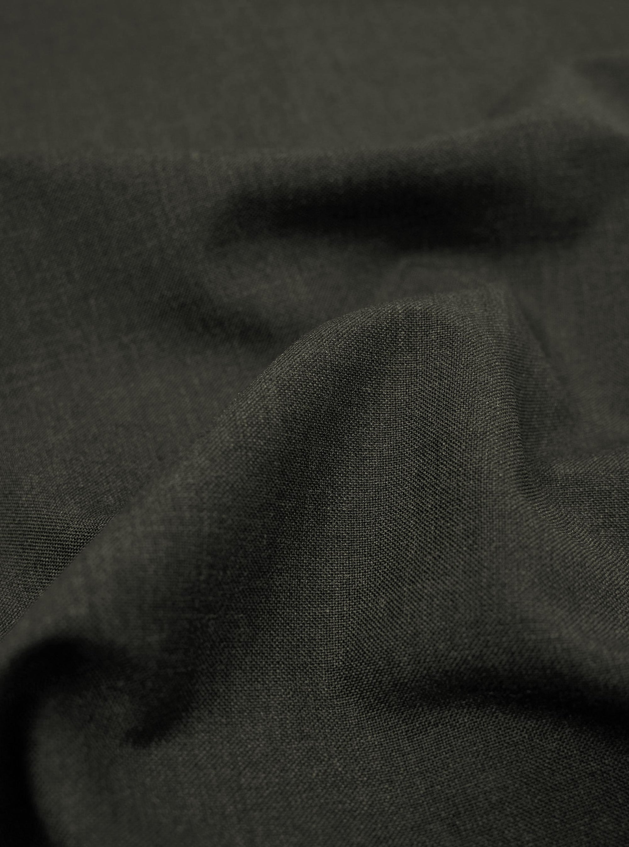 A close-up fabric swatch of the Olive Marl Tropical Suiting material used for the Two Button Jacket shows a detailed weave with a blend of green and grey tones. The image highlights the smooth, professional texture of the polyester-wool fabric.