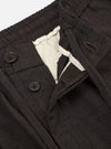 A pair of brown marl tropical suiting pleated track pants is displayed flat against a plain white background. The image highlights the loose, tapered fit and the textured, flecked appearance of the wool-blend fabric. Key details include an elasticated waistband with an adjustable drawstring and a single pleat at the front.