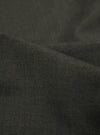 A detailed, close-up fabric swatch of the Olive Marl Tropical Suiting Pleated Track Pant shows the fine, textured weave of the olive green material.