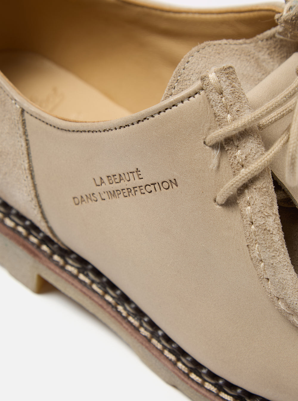 Close-up of Paraboot x Universal Works Michael shoe in sand leather/suede.  The shoe features the phrase "LA BEAUTE DANS L'IMPERFECTION" on the side. Shot on a white background.