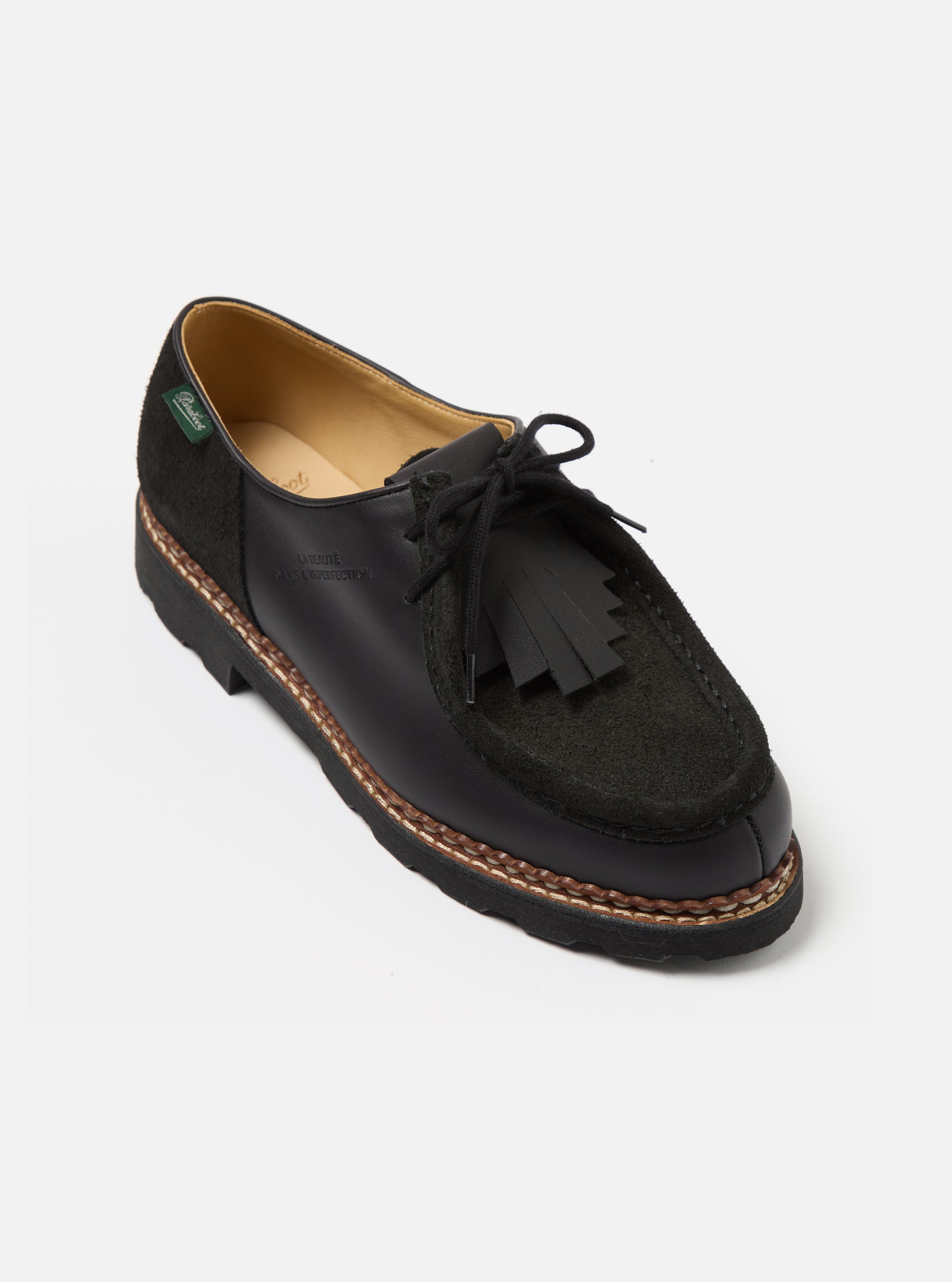 Studio shot of Paraboot x Universal Works Michael in Black Leather/Suede. The shoe features black leather and suede, with a fringed detail. Set against a white background.