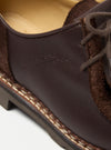 Close-up of the Paraboot x Universal Works Michael in Coffee Leather/Suede. Features brown leather and suede, with visible stitching on a white surface. "LA BEAUTE DANS L'IMPERFECTION" embossed.