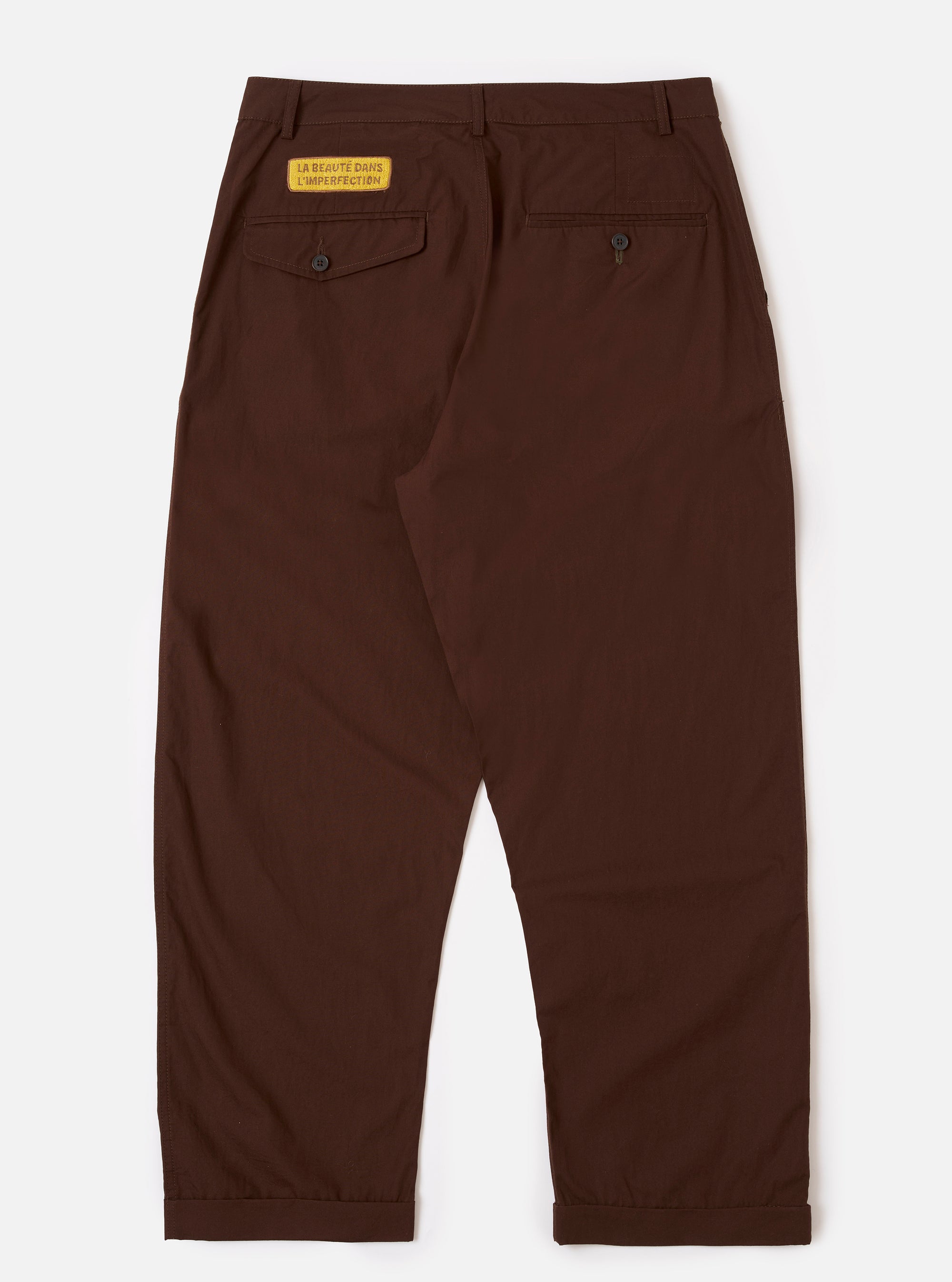 The Paraboot x Universal Works Brown Peached Poplin Super Chino is shown from a rear angle as a flat lay against a plain white background. The image highlights the two rear button-down welt pockets and the straight-cut design of the legs. The brown peached poplin fabric has a smooth, matte finish with visible stitching along the seams and waistband.