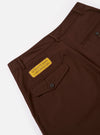 The Paraboot x Universal Works Brown Peached Poplin Super Chino is shown from a rear angle as a flat lay against a plain white background. The image highlights the two rear pockets, including one with a button-down flap, and the elasticated waistband. The rich brown peached poplin fabric features visible stitching details and a smooth texture.