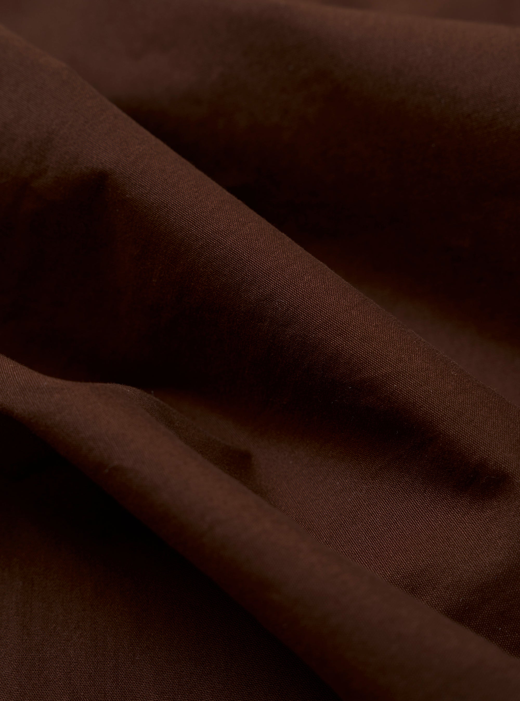 The Paraboot x Universal Works Brown Peached Poplin Super Chino is shown from a rear three-quarter angle as a flat lay against a plain white background. The image highlights the relaxed, straight-leg fit, the standard rear patch pockets, and the turn-up cuffed hem. The brown peached poplin fabric has a soft, matte finish.