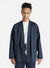 A model wears the Navy Twill Kyoto Work Jacket in a studio shot against a white backdrop. The jacket is a dark navy color with a tie closure.
