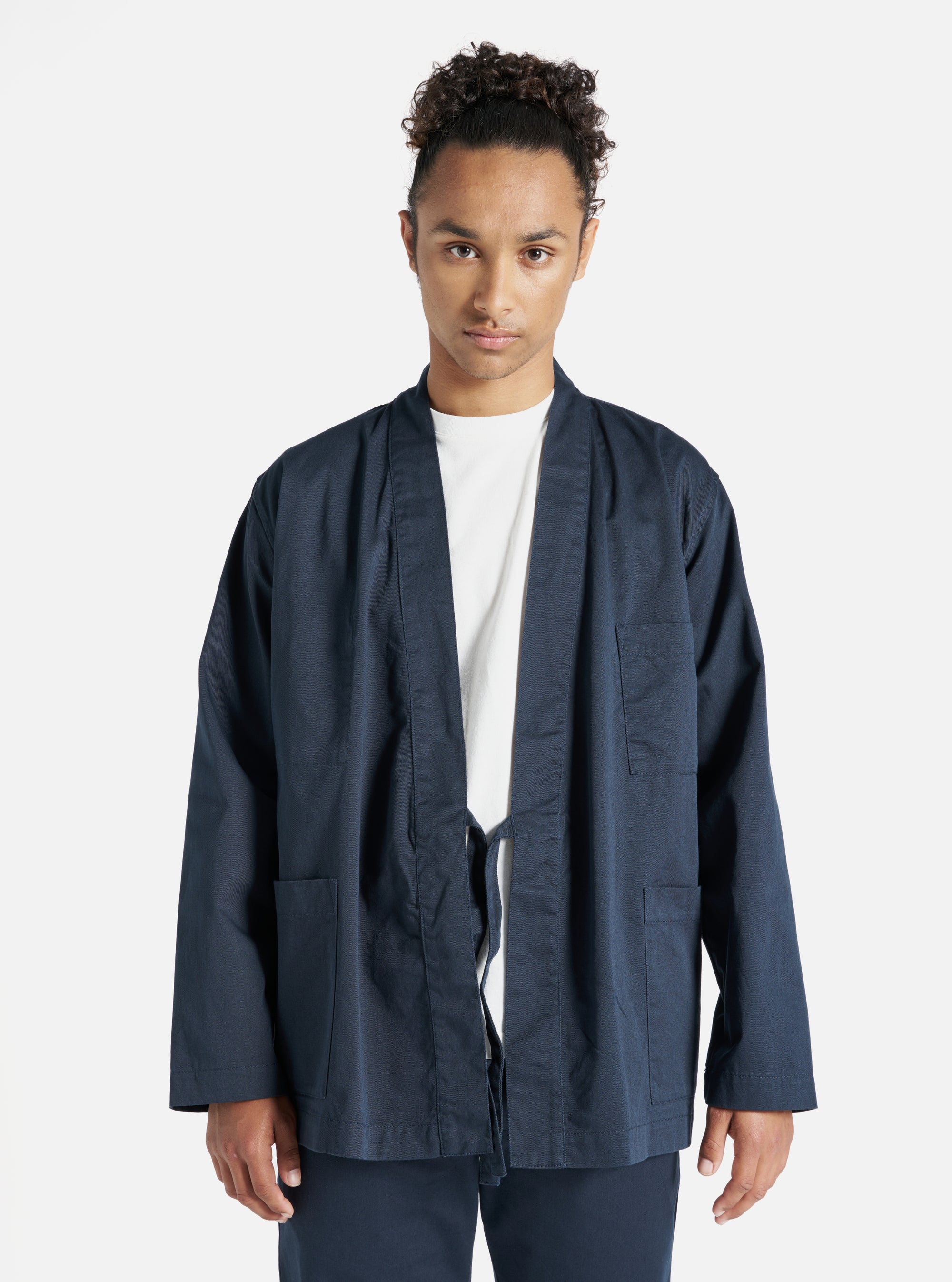 A model wears the Navy Twill Kyoto Work Jacket in a studio shot against a white backdrop. The jacket is a dark navy color with a tie closure.