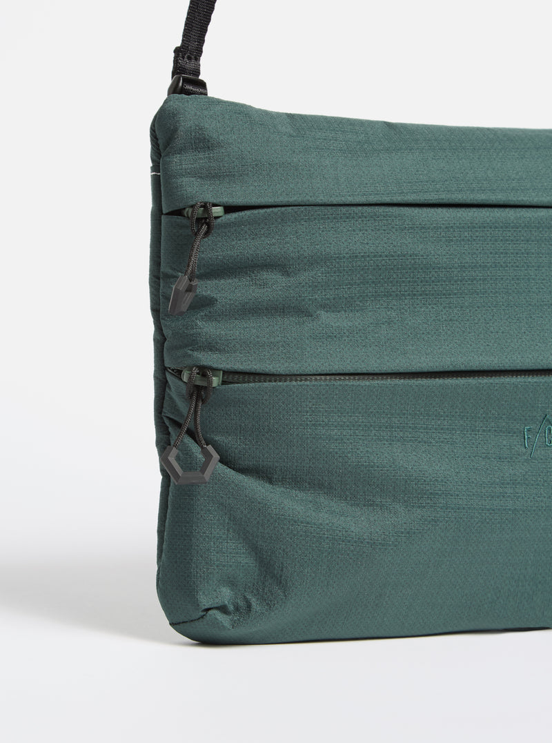 Close-up of the F/CE.® Green Nylon 2.5 Layer Sacoche on a white background. The bag features a textured green nylon material, black zippers, and a black adjustable strap.
