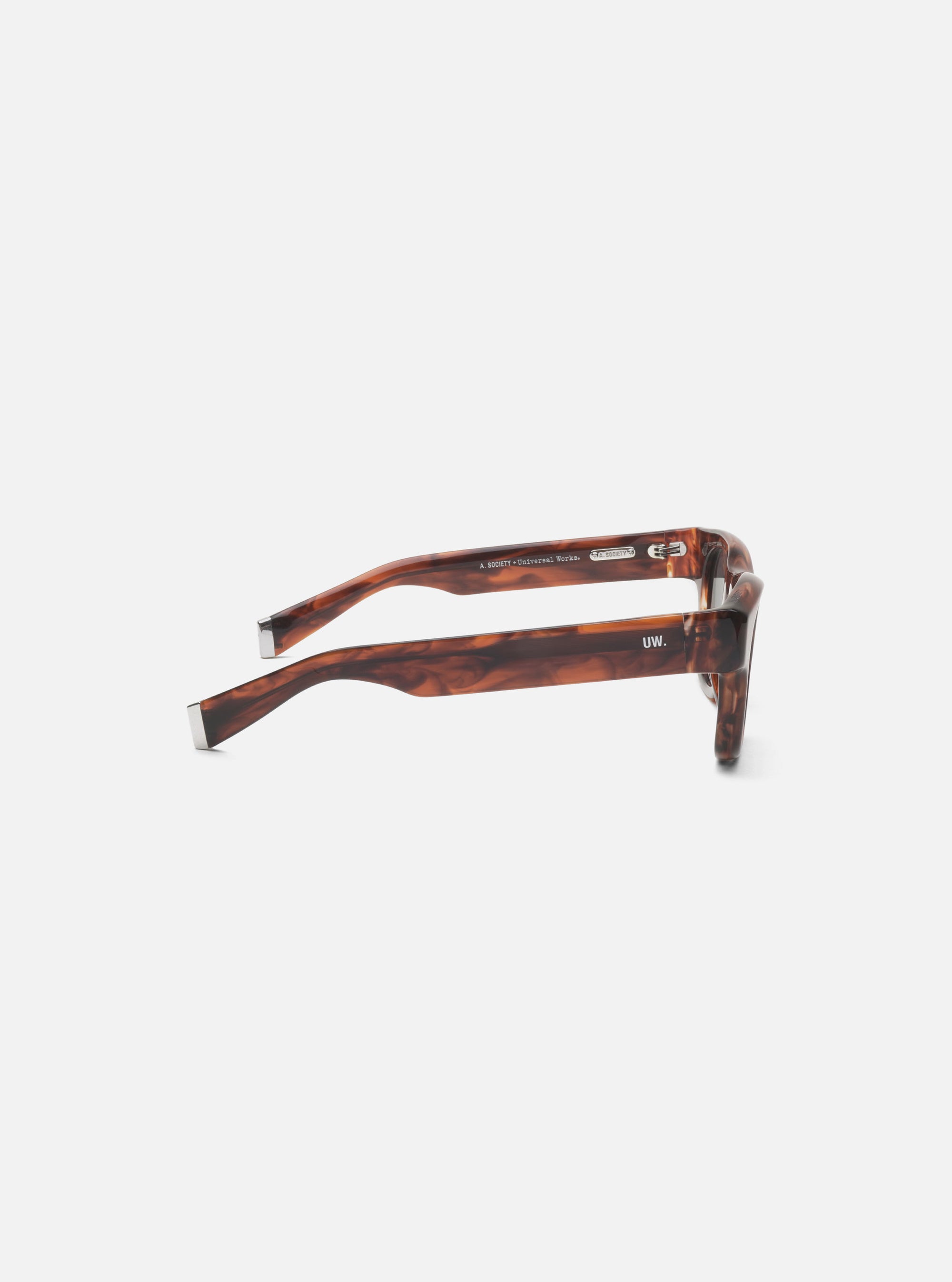Side view of A. SOCIETY x Universal Works Brown Stanley Sunglasses on a white surface. The frame is brown with a marbled pattern and silver accents.