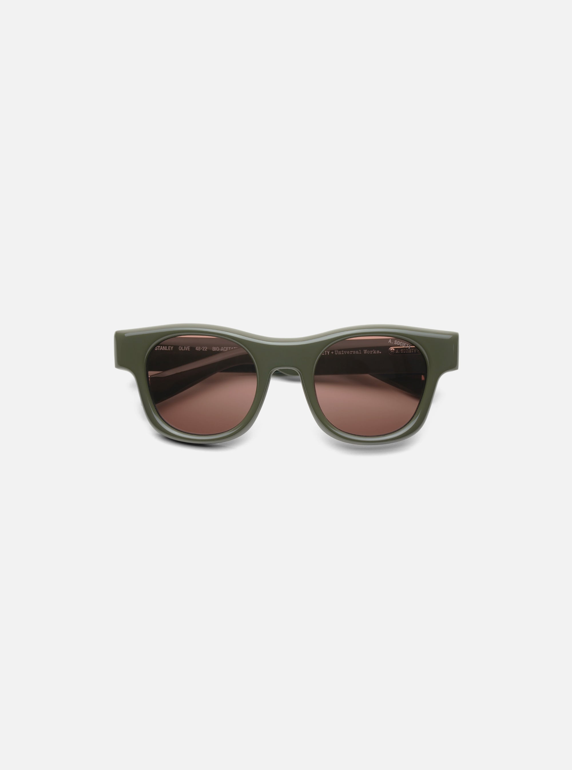 A. SOCIETY x Universal Works Olive Stanley Sunglasses on a white background. The frames are olive green and the lenses are brown.