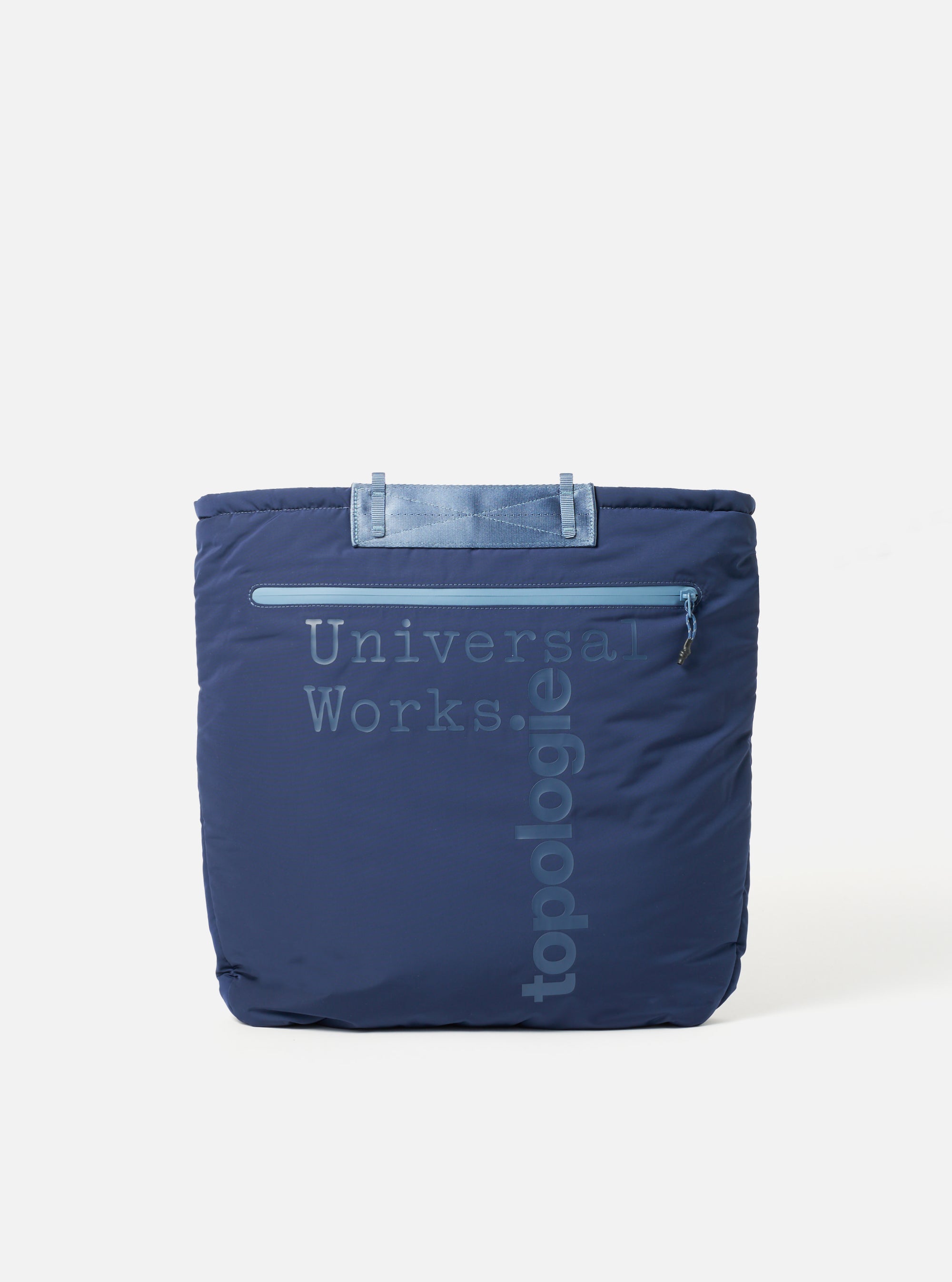 The Topologie x Universal Works Insignia Blue UW Tech Helmet Bag. A blue padded bag with 'Universal Works' and 'Topologie' printed on the front. Shot on a white background.