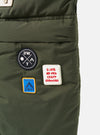 Close-up of the Topologie x Universal Works Rifle Green UW Tech Helmet Bag. Patches add detail to the olive green material. Shot against a white backdrop.