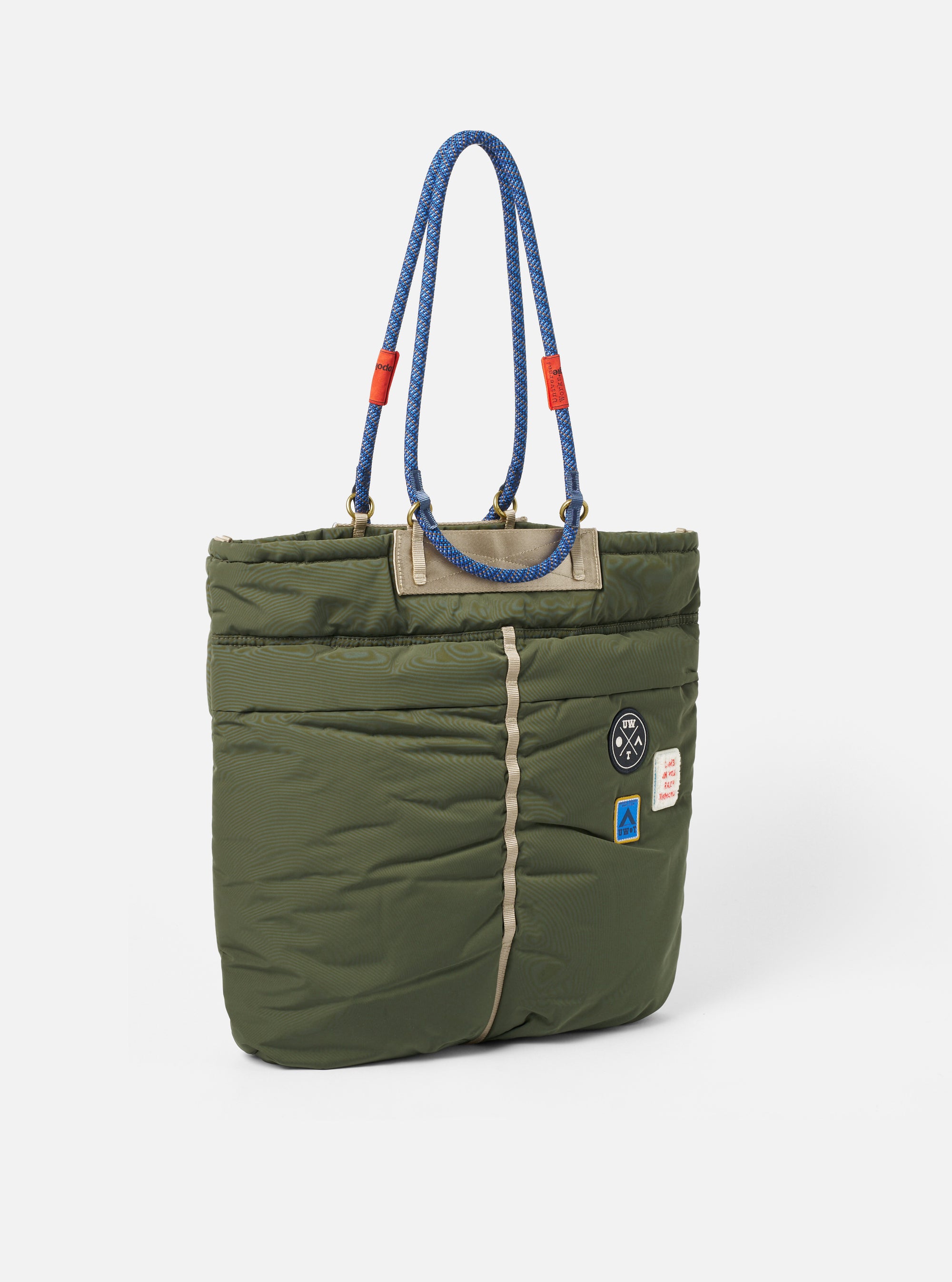Topologie x Universal Works Rifle Green UW Tech Helmet Bag in a studio shot. The bag is green with blue rope handles and patches. 