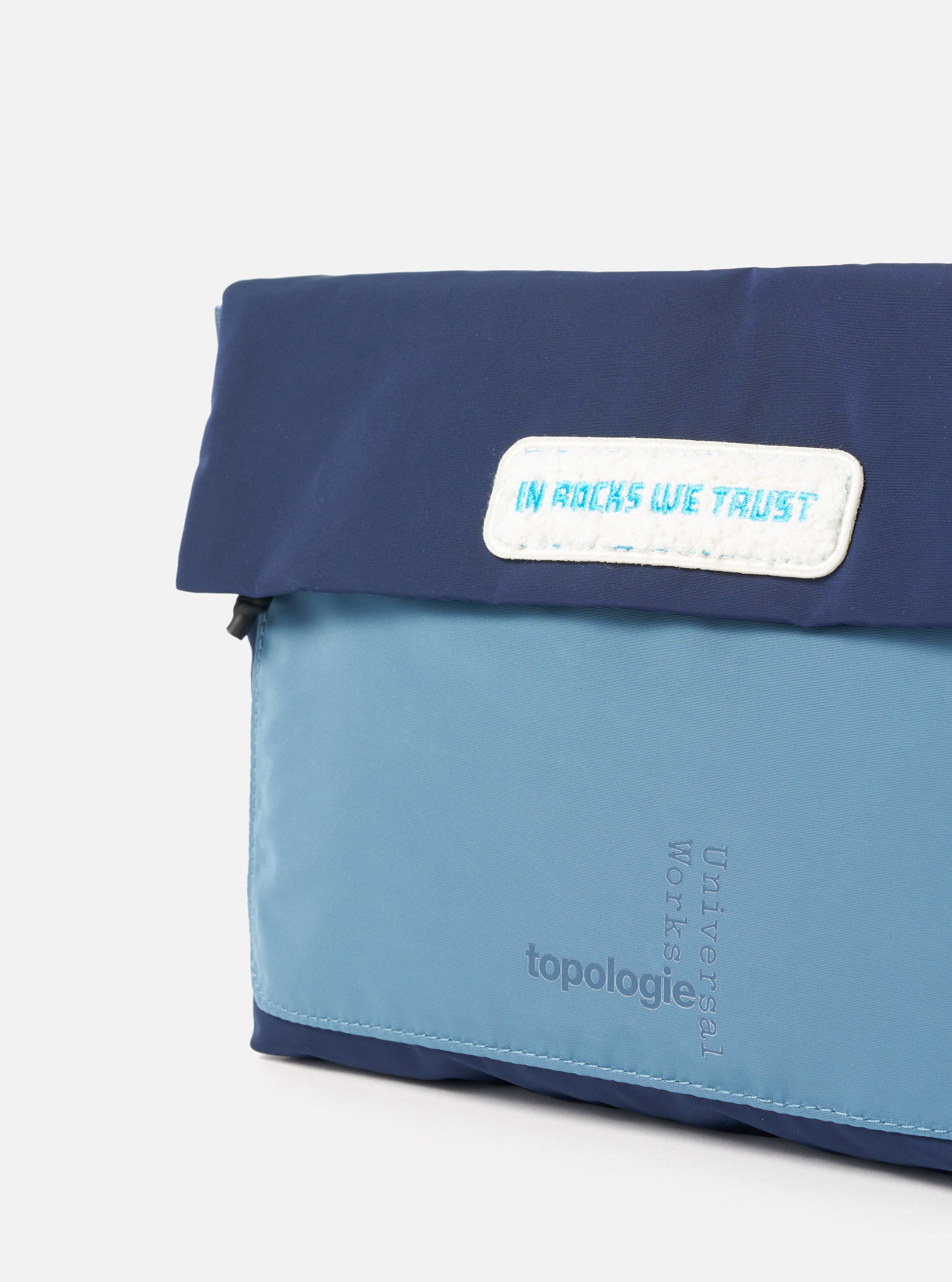 Close-up of the Topologie x Universal Works Insignia Blue UW Tech Musette Medium. Features two-tone blue nylon, white logo patch, and subtle branding on a clean white background.