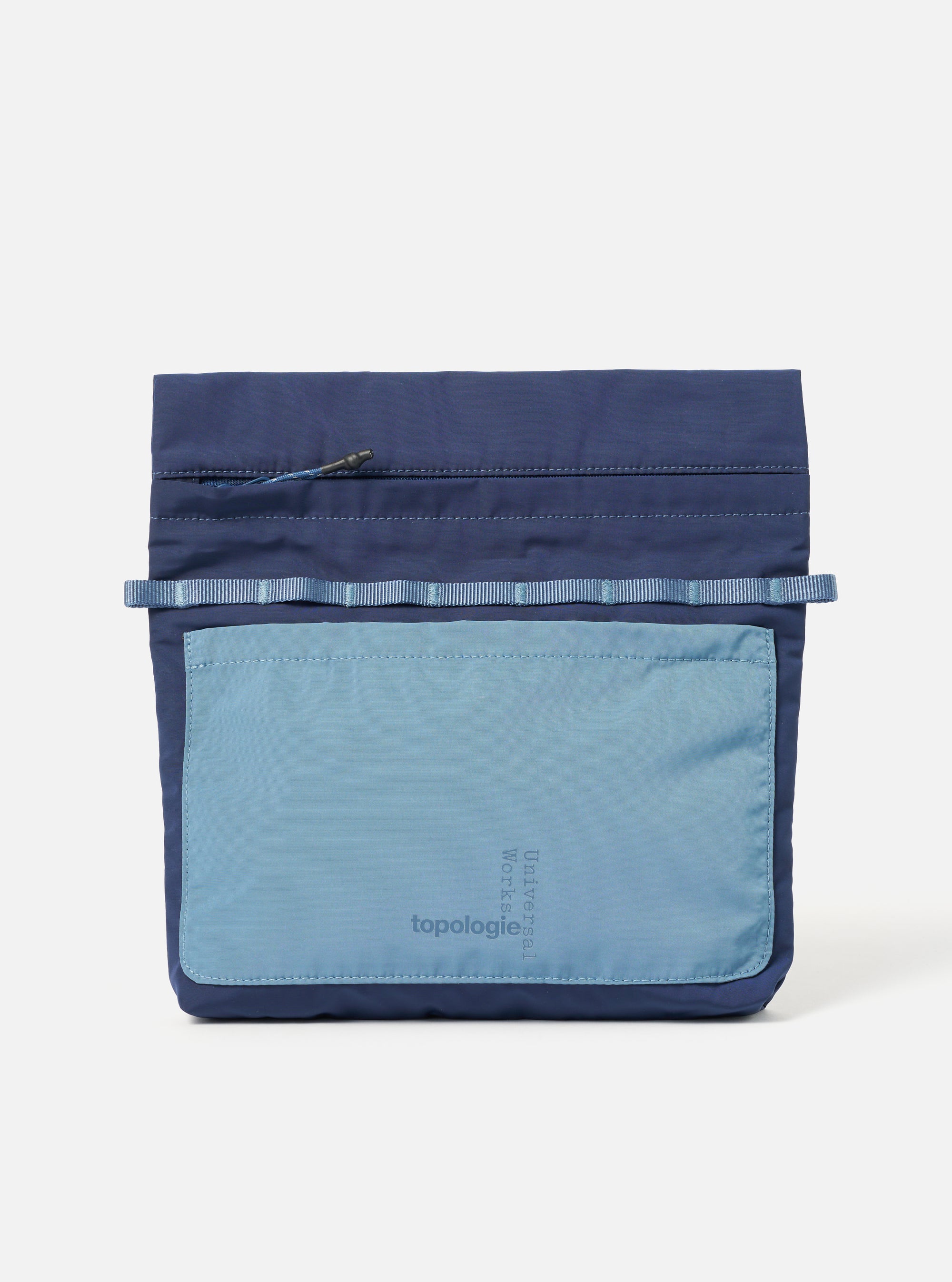 The Topologie x Universal Works Insignia Blue UW Tech Musette Medium bag on a white background. The bag is blue with a lighter blue pocket featuring the brand logos.