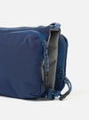 Close-up of the Topologie x Universal Works Insignia Blue UW Tech Bottle Sacoche Medium. The blue bag features a gray interior and blue zipper pulls. Shot on a white background.
