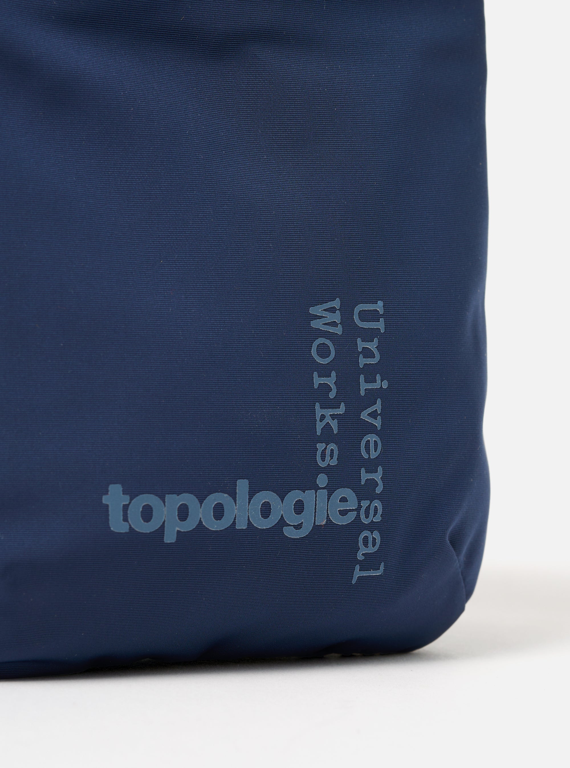Close-up of the Topologie x Universal Works Insignia Blue UW Tech Phone Sacoche. The blue fabric bag features the brand logos in a lighter blue. Shot against a white background.
