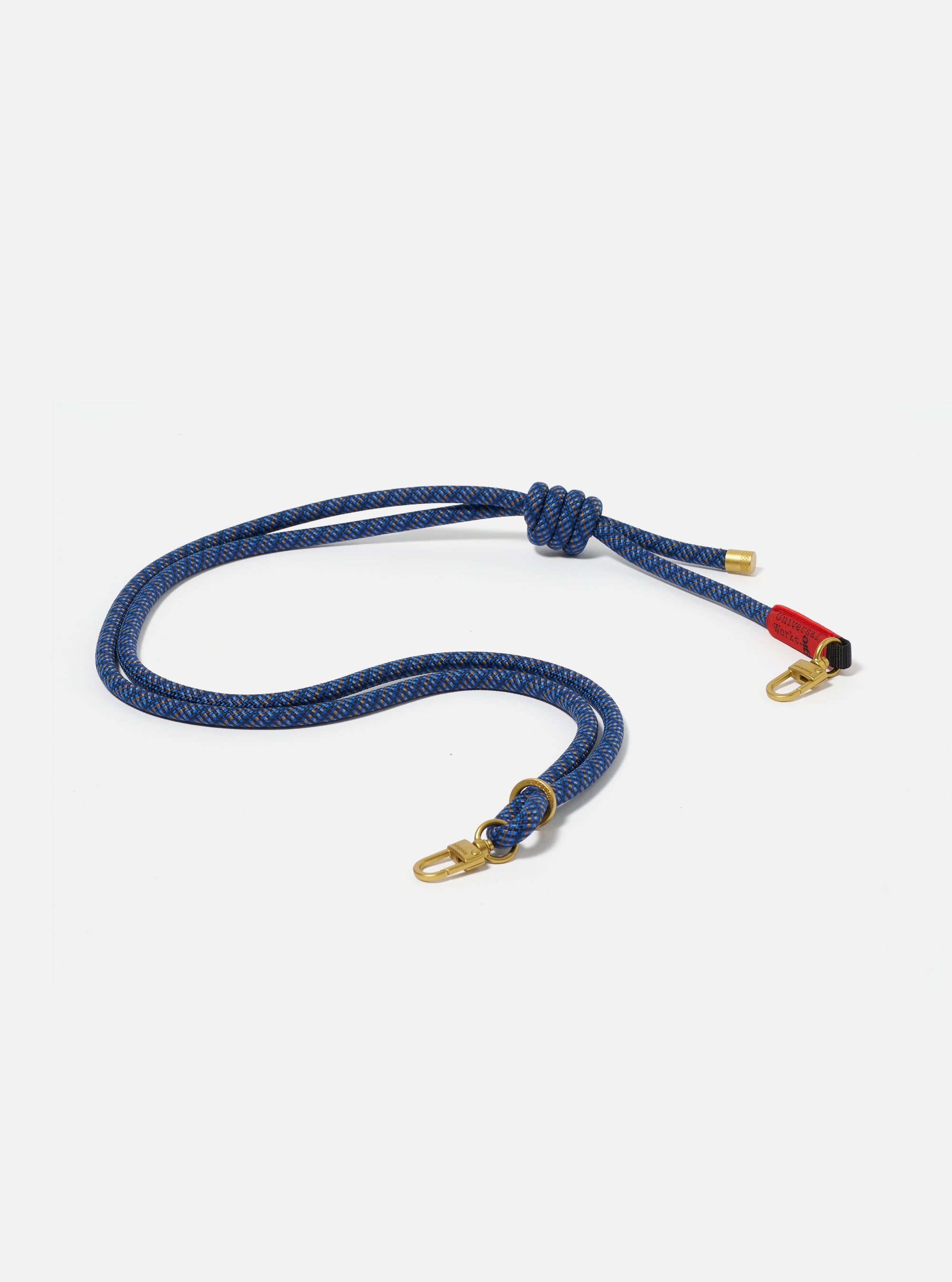 The Topologie x Universal Works Navy Hitch UW Rope 8mm Rope Strap on a white background. The strap is blue with gold hardware and red accents.
