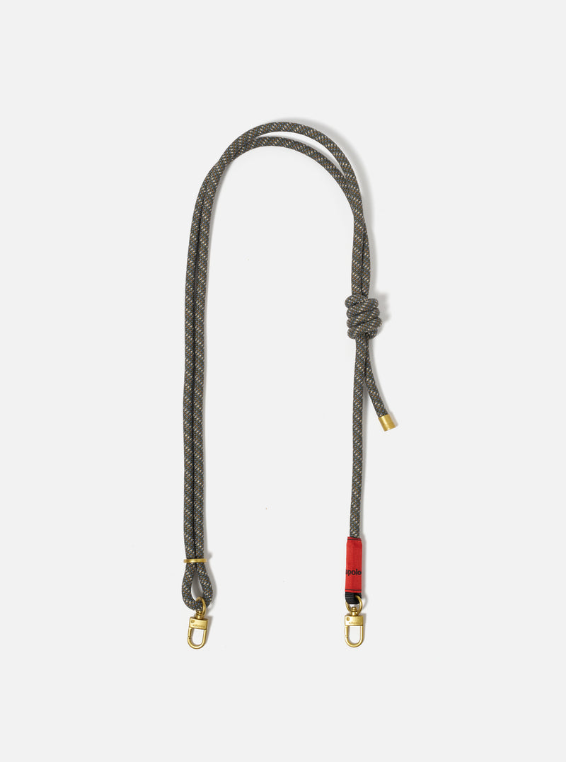 The Topologie x Universal Works Red Hitch UW Rope 8mm Rope Strap on a white background. The strap is gray and brown with gold hardware and a red accent.