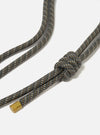 Close-up of the Topologie x Universal Works Red Hitch UW Rope 8mm Rope Strap. The rope is a mix of blue, brown, and beige, knotted on a white background. Gold metal end.