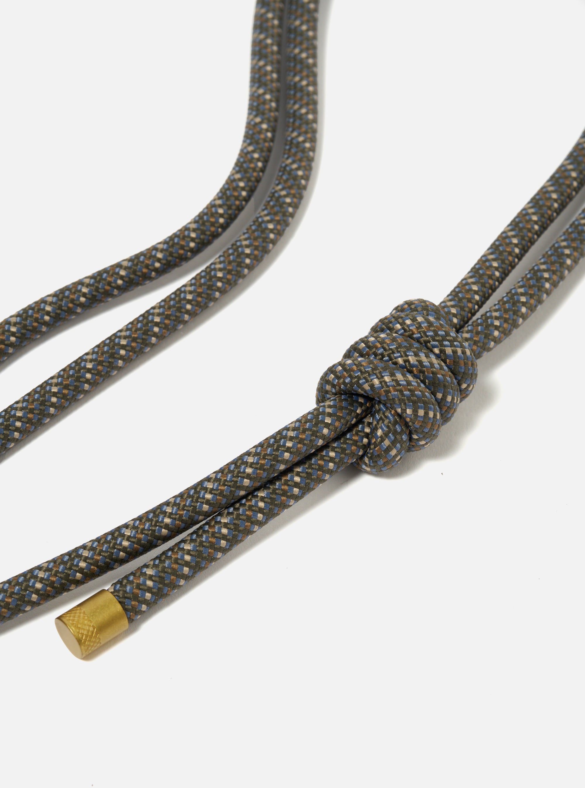 Close-up of the Topologie x Universal Works Red Hitch UW Rope 8mm Rope Strap. The rope is a mix of blue, brown, and beige, knotted on a white background. Gold metal end.