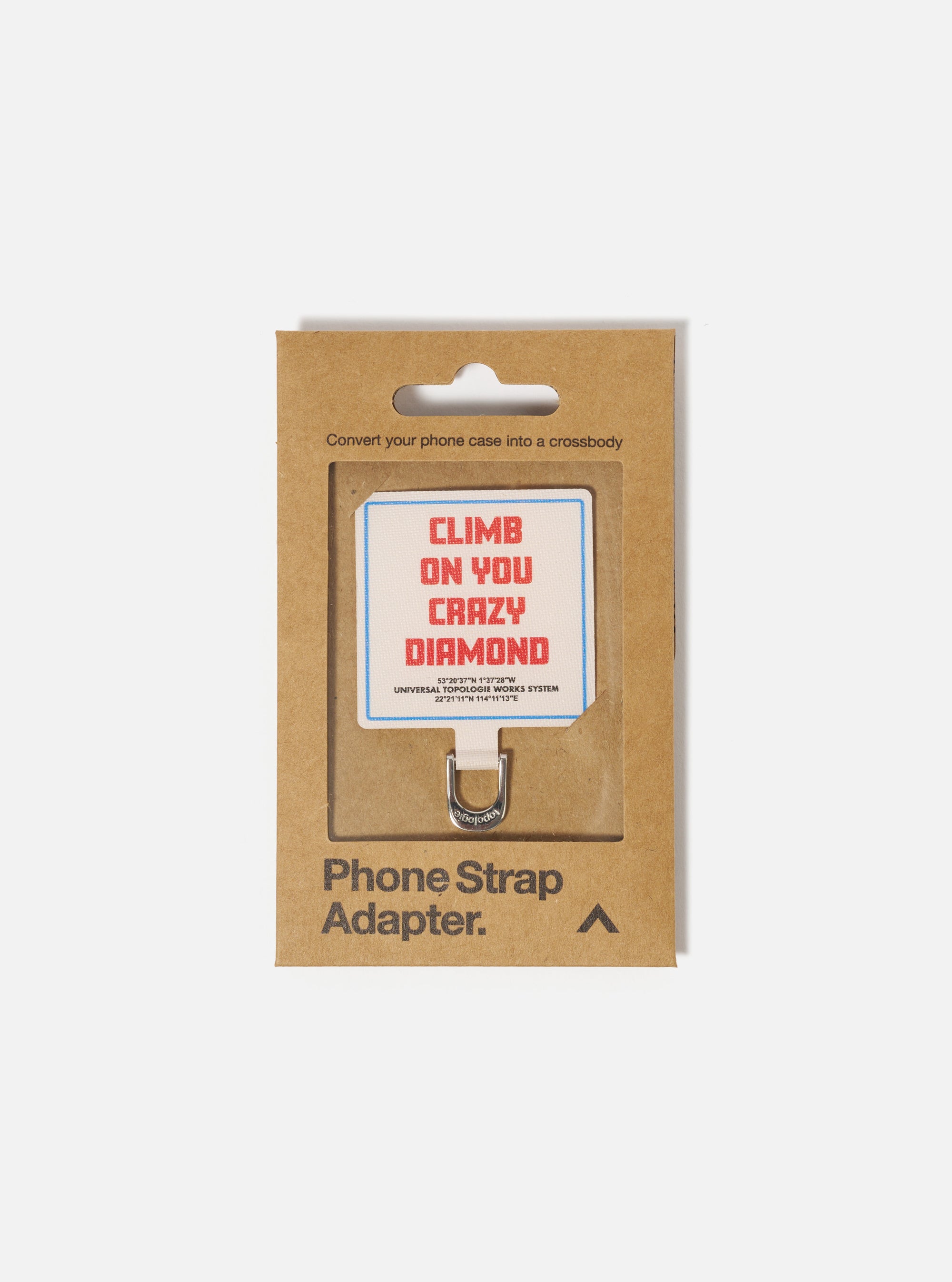 Topologie x Universal Works Off White UW Tech Phone Strap Adapter in its brown cardboard packaging. The adapter has a white fabric with "Climb on you crazy diamond" printed on it.