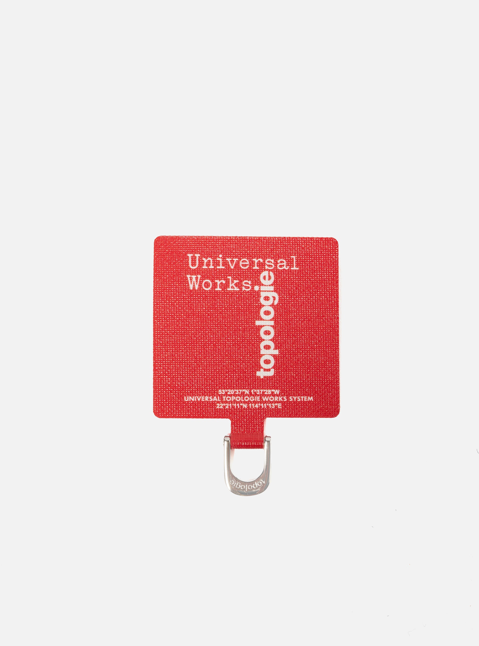 Close-up of the Topologie x Universal Works Red UW Tech Phone Strap Adapter on a white background. The red adapter features the logos of both brands.