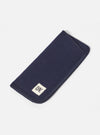 A Navy Melton Large Glasses Case on a white surface. The case is made of dark blue melton wool and has a small white tag with black lettering. 