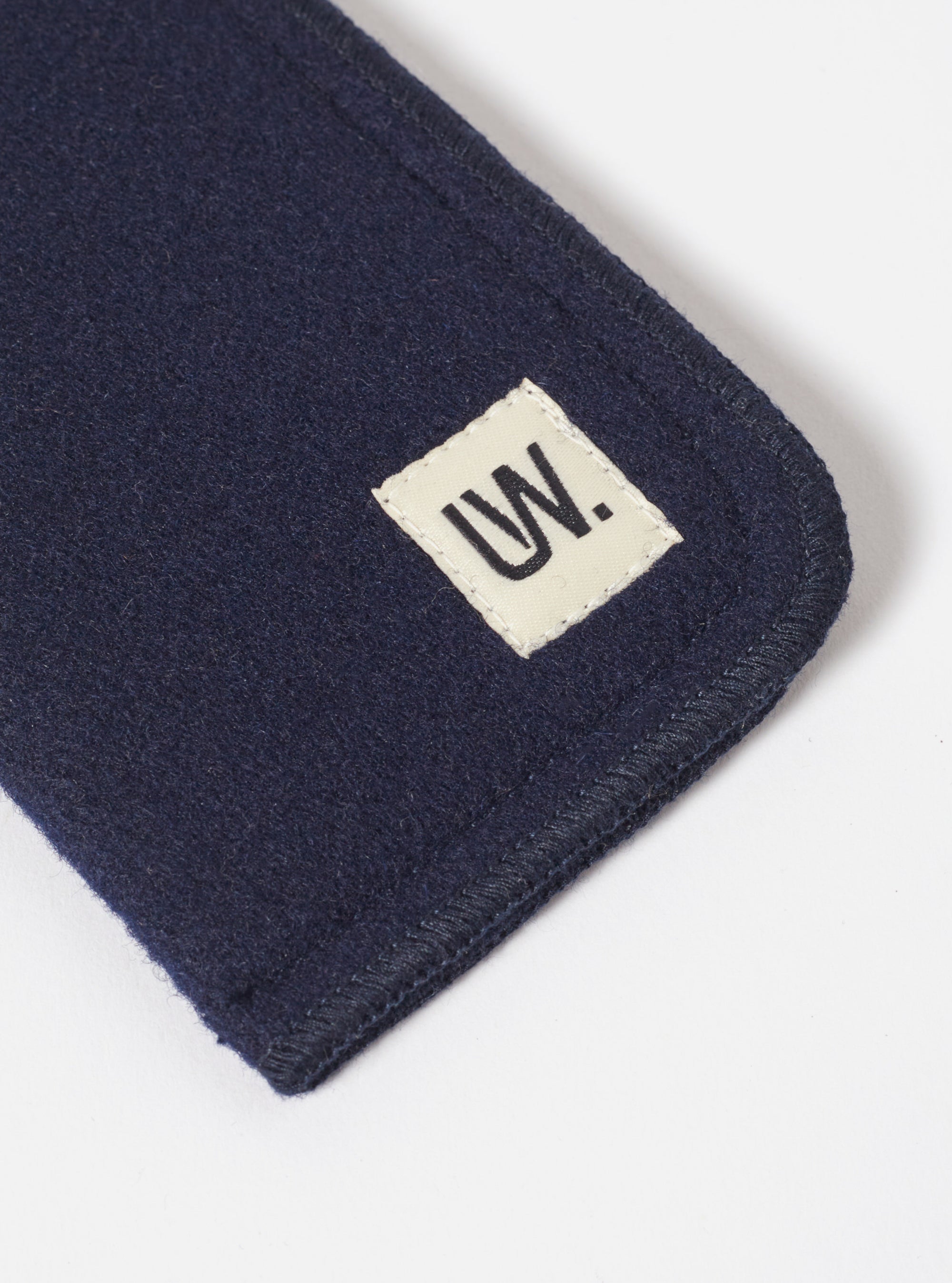 Close-up of the Navy Melton Large Glasses Case on a white surface, showing the melton wool texture and the 'UW' logo patch.