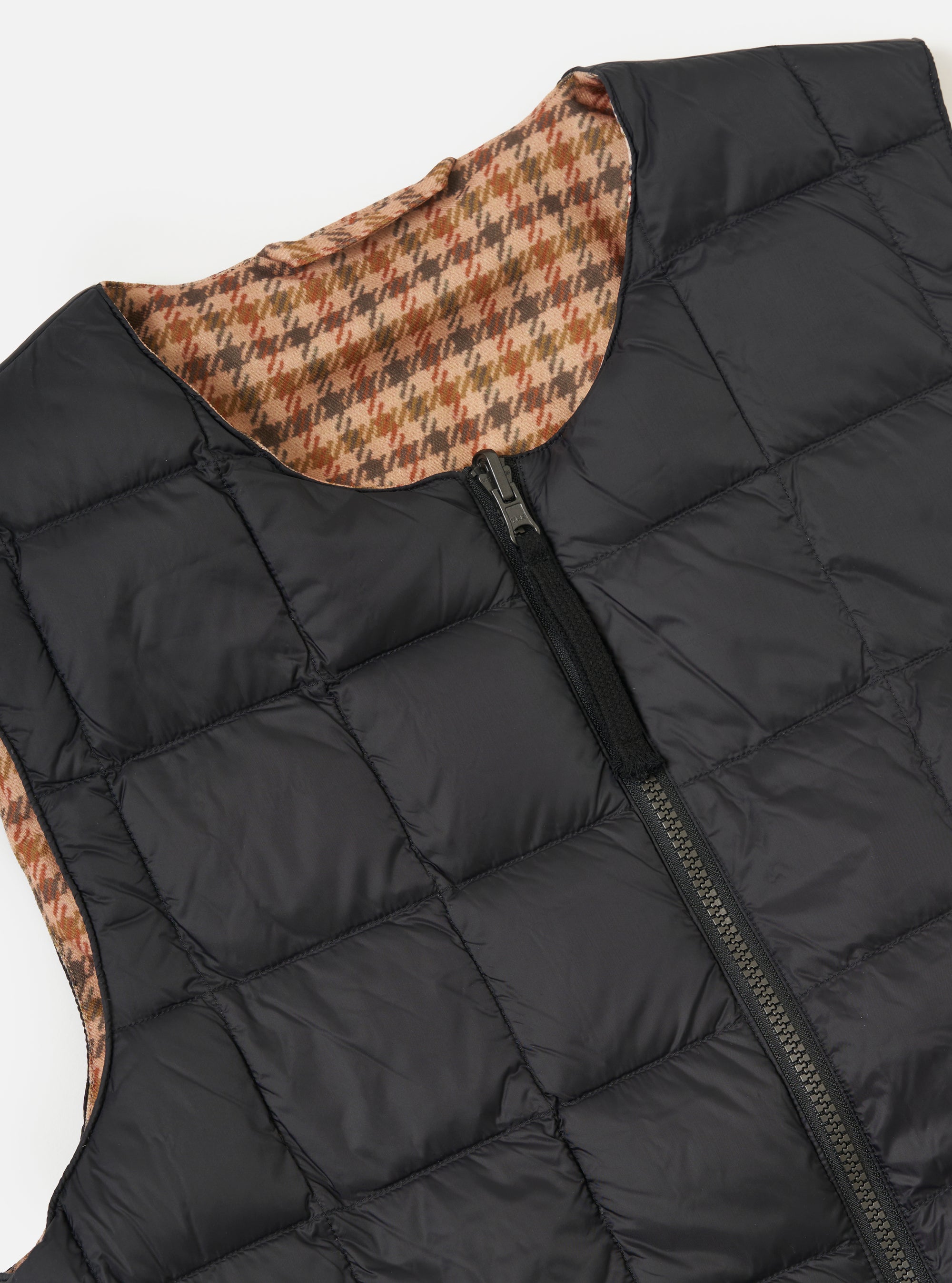 Close-up of the TAION x Universal Works Reversible Black Military Line Vest on a white background. The vest is black with a quilted pattern and a visible brown houndstooth pattern on the reverse side.