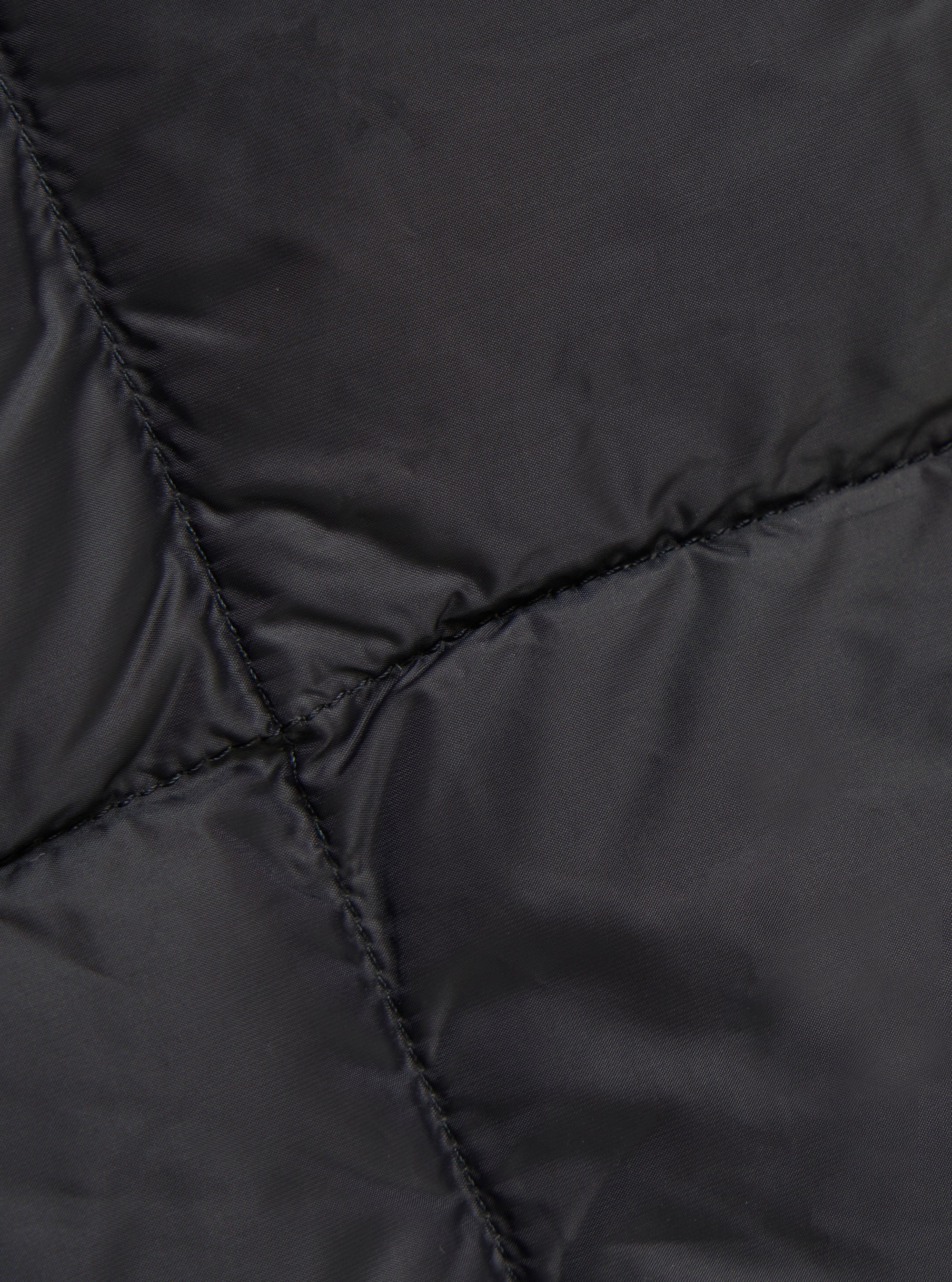 Close-up of the TAION x Universal Works Reversible Black Military Line Vest, showcasing the quilted pattern and material. The vest is laid flat, highlighting the texture.
