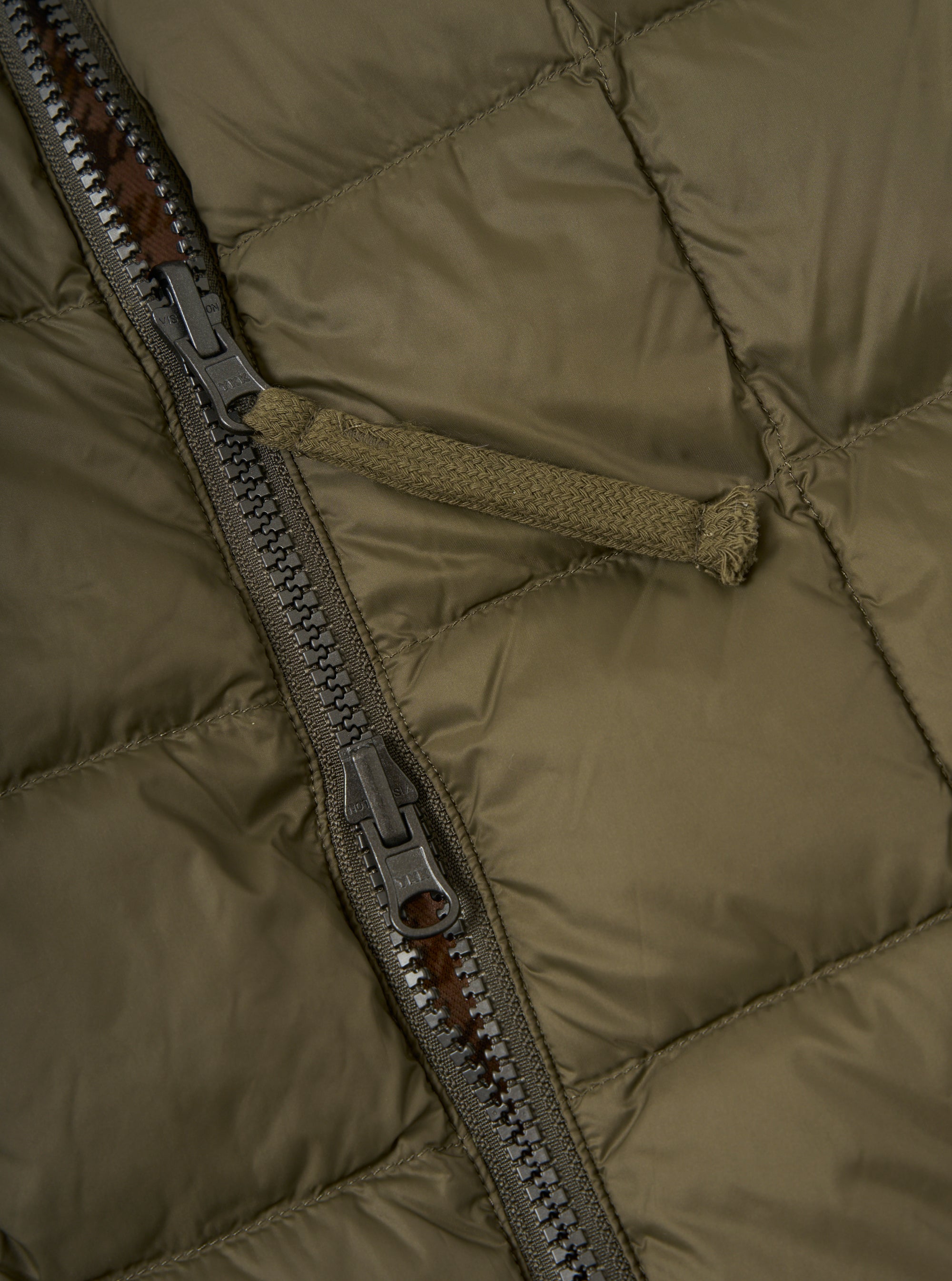 Close-up of the TAION x Universal Works Reversible Dark Olive Military Line Vest. Shows the olive green quilted material and zipper detail. 