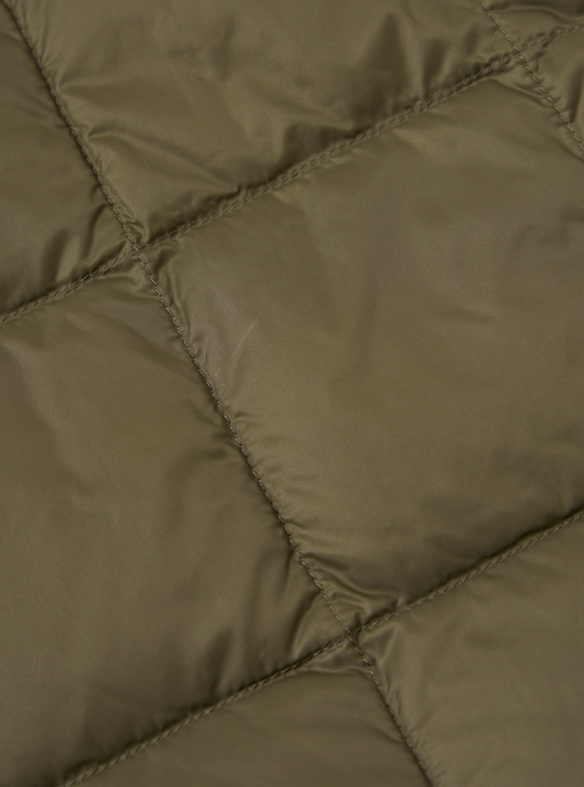 Close-up of the TAION x Universal Works Reversible Dark Olive Military Line Vest. Shows the dark olive quilted material and stitching.