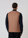 Back view of a model wearing the TAION x Universal Works Reversible Black Military Line Vest. The vest has a brown and tan houndstooth pattern. The model is on a white background.