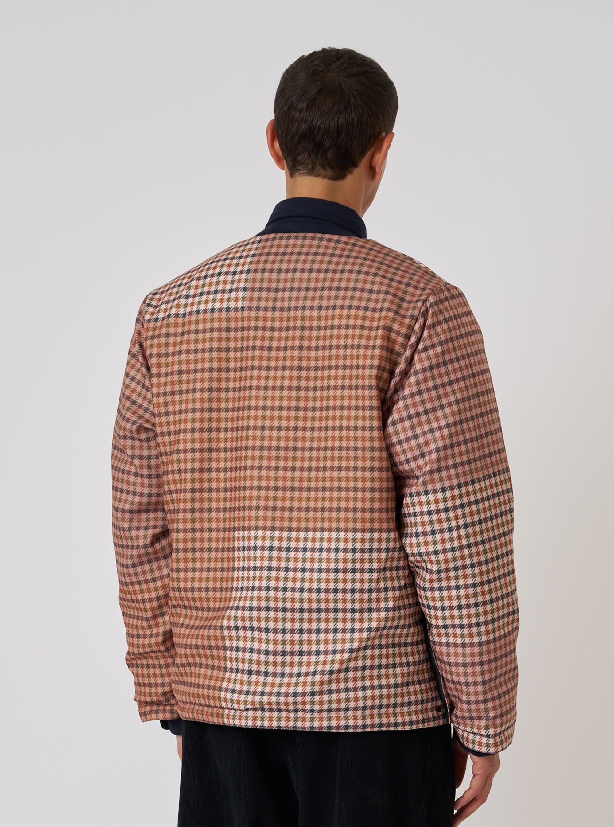 Back view of a model wearing the TAION x Universal Works Reversible Dark Navy Military Line Liner Jacket. The jacket has a brown and tan check pattern. Shot against a white backdrop.